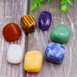 Polished natural chakra stone set on wood background with 7 rainbow crystal gems