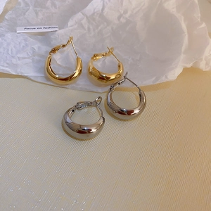 Vue à plat de boucles d'oreilles créoles dorées et argentées sur fond mode texturé