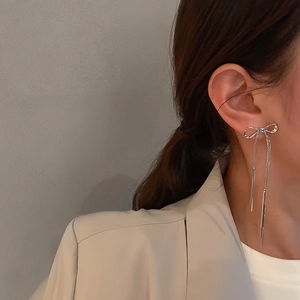 Silver bow earrings with long diamond tassels worn by a model in a lifestyle shot
