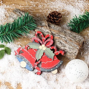 Creative wooden Christmas tree ornament with red bells and holly leaves on snow background