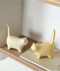 Detail of modern ceramic cat figurines with a matte finish on a minimalist shelf
