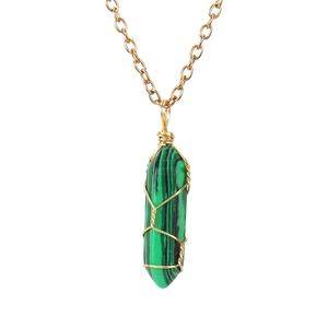 Macro view of wire-wrapped green malachite hexagonal prism pendant on gold chain necklace