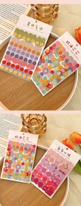 Macro shot of bubble dot and flower stickers on a desk with tulips and open book