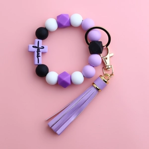 Close-up of silicone beaded keychain with Jesus cross charm and purple tassel detail