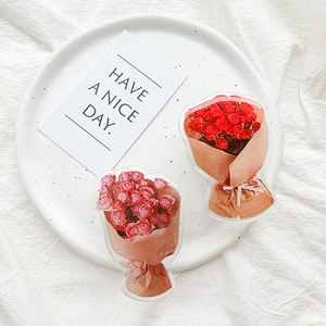 Detail of red and pink acrylic rose bouquet brooches displayed on a white dotted plate