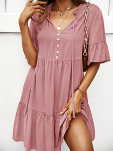 Détail de la robe rose à col en V avec volants aux manches et boutons blancs sur la poitrine