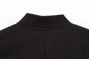 Detailaufnahme von Rippkragen und hochdichtem Köpergewebe an einer schwarzen Jacke