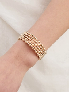 Close-up of five-layer gold beaded bracelet with sparkling white crystals on a wrist