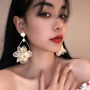 Elegant oversized beige fabric flower earrings with crystal beads on a model