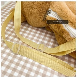 Detail of smooth white zipper and adjustable yellow strap on brown plush dog backpack