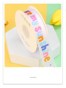Detail of white polyester ribbon roll with colorful SunShine print for gift wrapping