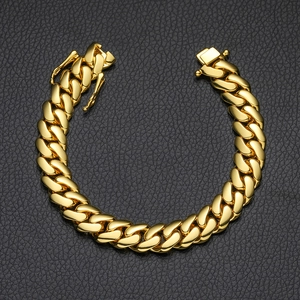 Macro shot of gold cuban link chain bracelet with butterfly buckle on black leather