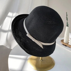 Chic black straw sun hat with cream ribbon bow on a stylish gold stand