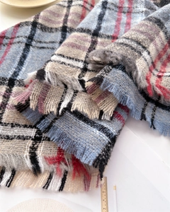 Detailed close-up of soft plaid scarf fabric texture and fringed edges in blue and grey