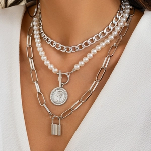 Detailed view of layered baroque pearl necklace with silver coin and lock pendants
