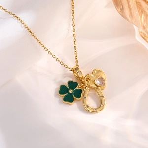 Detail of gold necklace featuring green clover, crystal heart, and horseshoe charms