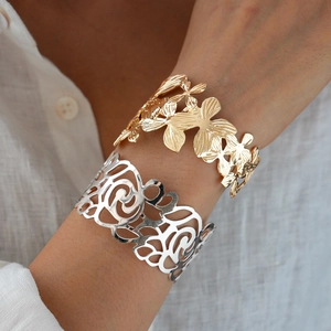 Detailed close-up of gold flower and silver swirl wide open cuff bracelets for women