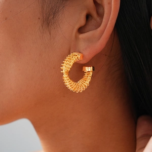 Close-up of 24k gold-plated twisted C-shape earrings showing spiral texture on model