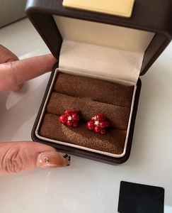 Macro shot of red floral stud earrings with zircon center displayed in a jewelry box