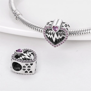 Detail of silver heart charm with purple zircon inlay and heartbeat engraving on bracelet