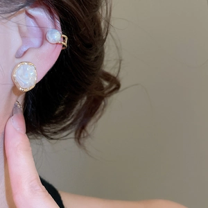 Close-up of irregular pearl ear clip with gold metal trim on model ear