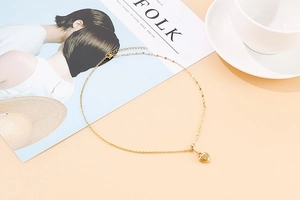 Detail of elegant gold heart pendant necklace on minimalist fashion magazine background