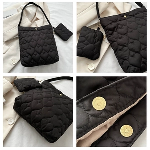 Detail view of black heart-quilted bucket bag with magnetic closure and coin purse