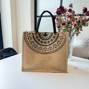 Detail view of ethnic jute tote bag with black geometric patterns and round handles