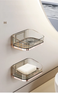 Macro detail of wall-mounted gray acrylic soap holder with protective rails and drain bar