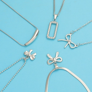 Assorted silver titanium steel necklaces featuring geometric tubes and bow pendants