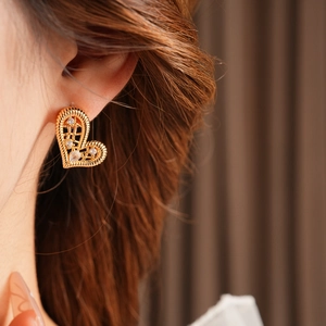 Close-up of gold-plated heart earrings with sparkling cubic zirconia on a model's ear