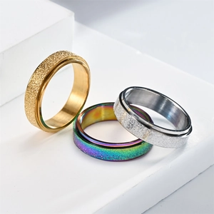 Close-up of three 6mm rotating fidget rings in gold, silver, and iridescent frosted steel