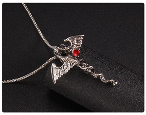 Gros plan du pendentif dragon en argent avec cristal rouge sur fond de cuir noir