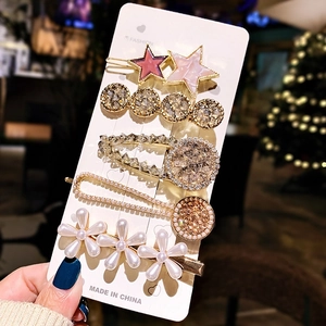 Close-up of five-piece rhinestone and pearl hair clip set on display card with warm bokeh
