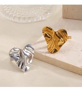 Detailed view of irregular heart rings in gold and silver finish on stone pedestals