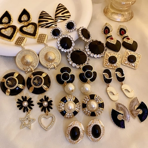 Flat lay of vintage gold and black enamel earrings with pearls on beige fabric