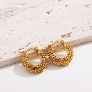 Detailed macro view of 18K gold plated twisted hoop earrings with textured bead pattern