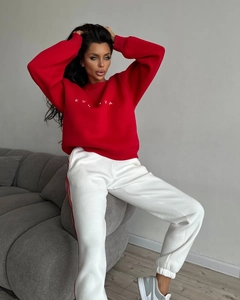 Detail of red crewneck sweatshirt with white embroidery and striped matching track pants