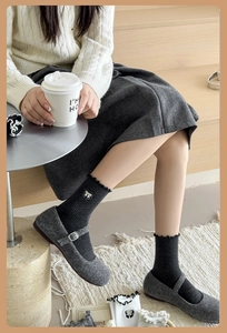 Detail of gray Mary Jane shoes with black knit bow socks in a cozy lifestyle setting