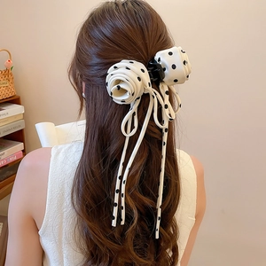Detailed back view of a white polka dot fabric hair claw clip with large rose and ribbons