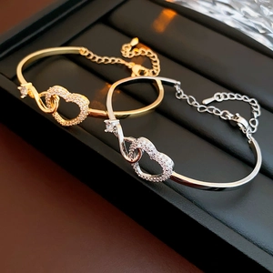 Detail of gold and silver heart bracelets with cubic zirconia on black jewelry tray