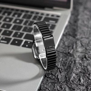 Minimalist square quartz watch with black stainless steel mesh band on a silver laptop