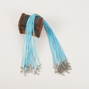 Close-up of blue necklace cords with silver lobster clasps on a decorative wooden box