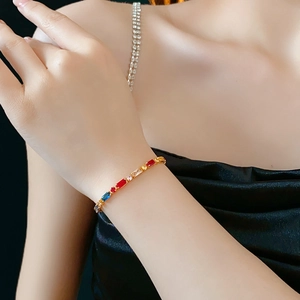 Macro shot of gold-plated bracelet with multi-colored rectangular zircons on wrist
