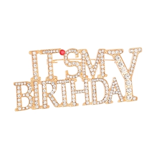 Detail of gold metal birthday brooch with sparkling rhinestones and clear lettering