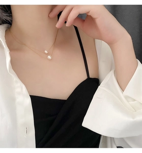 Close-up of double layer gold titanium steel necklace with elegant natural pearls