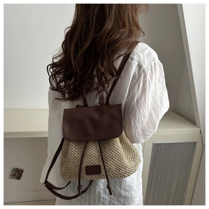 Detail of straw backpack with brown leather strap worn by model on back