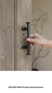 Detailed view of vintage black cast iron door handle with hammered texture on rustic wood