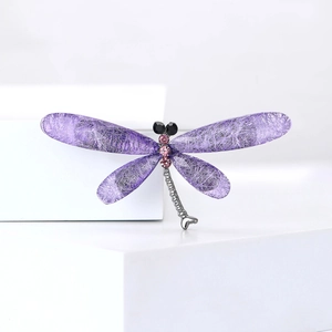 Elegant silver dragonfly brooch with purple rhinestones on minimalist white display