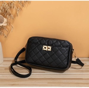 Nahaufnahme einer schwarzen Stepptasche mit goldenem Drehverschluss und Schulterriemen